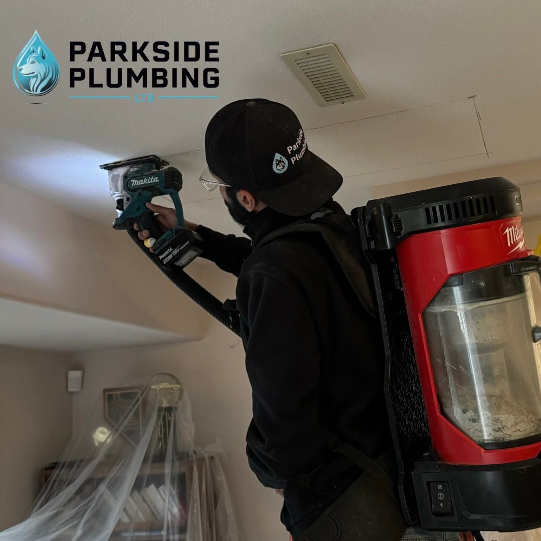A man is using a vacuum cleaner to clean a ceiling for parkside plumbing