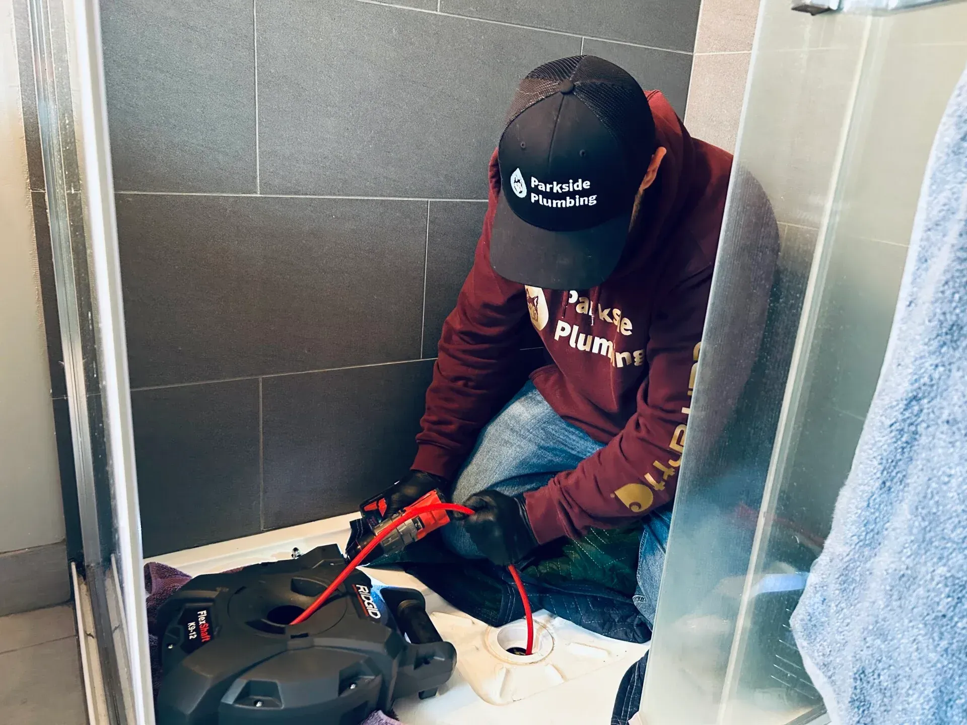 A man is kneeling down in a bathroom using a machine.