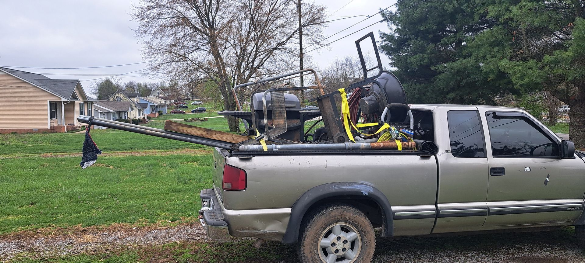 A pickup truck with a trailer attached to the back is parked in a grassy field.