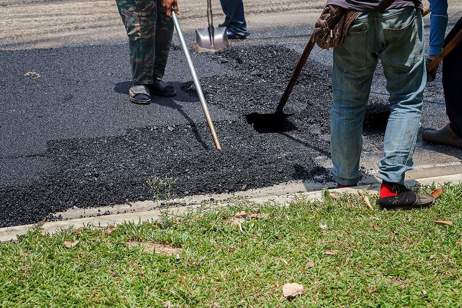 Road workers paving a street, using tools to spread and level asphalt.