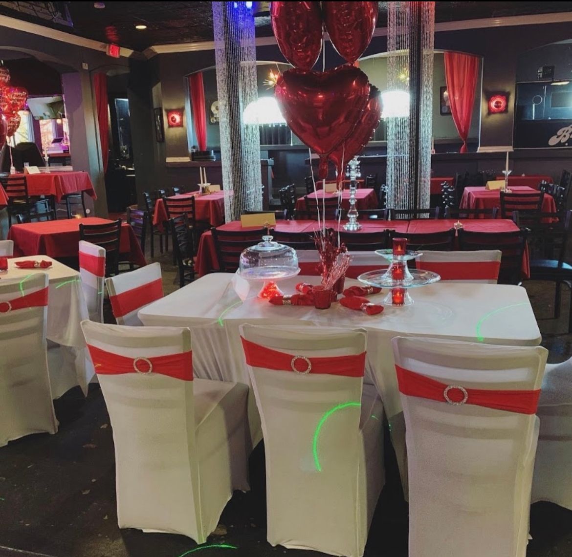 Restaurant decorated for Valentine's Day with red and white tablecloths, heart balloons, and chair sashes.
