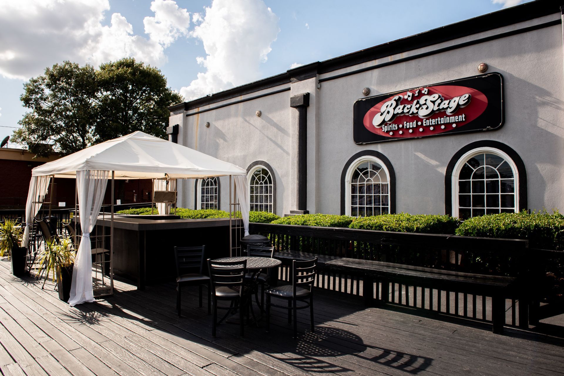 Exterior of The Brass Stage, a venue with outdoor seating under a canopy, black benches, and a sign.
