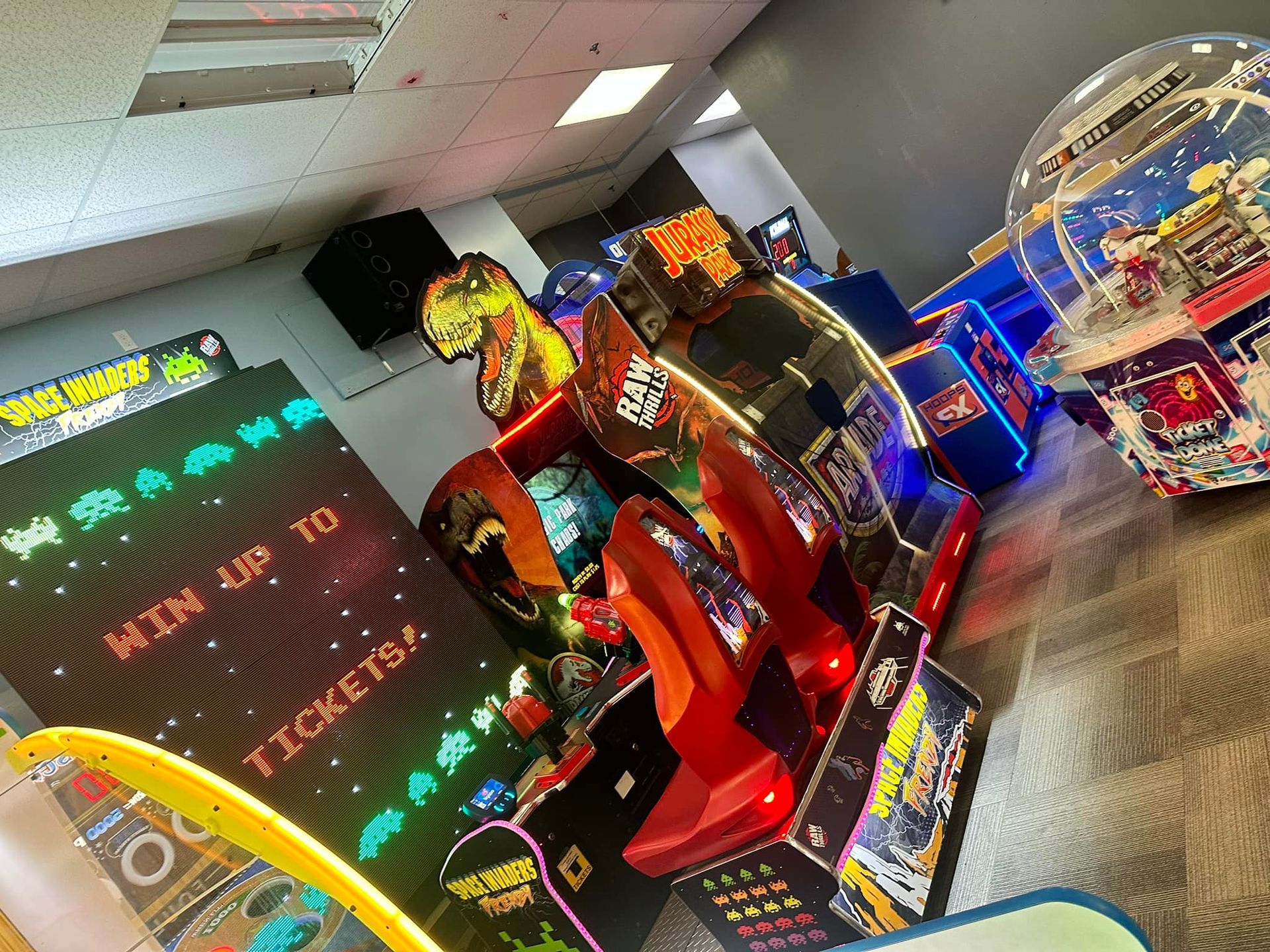 A bunch of arcade games are lined up in a room.