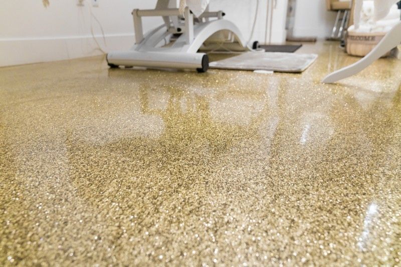 Shiny gold glitter epoxy floor reflecting light, under a white medical chair.
