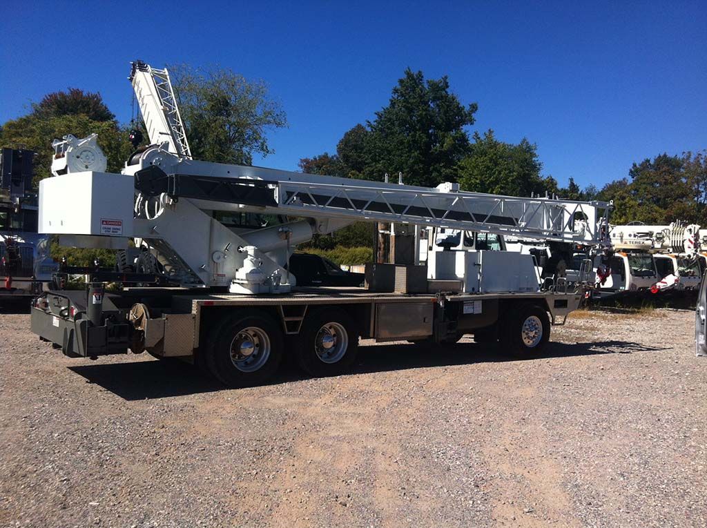 A large white truck is parked in a gravel lot