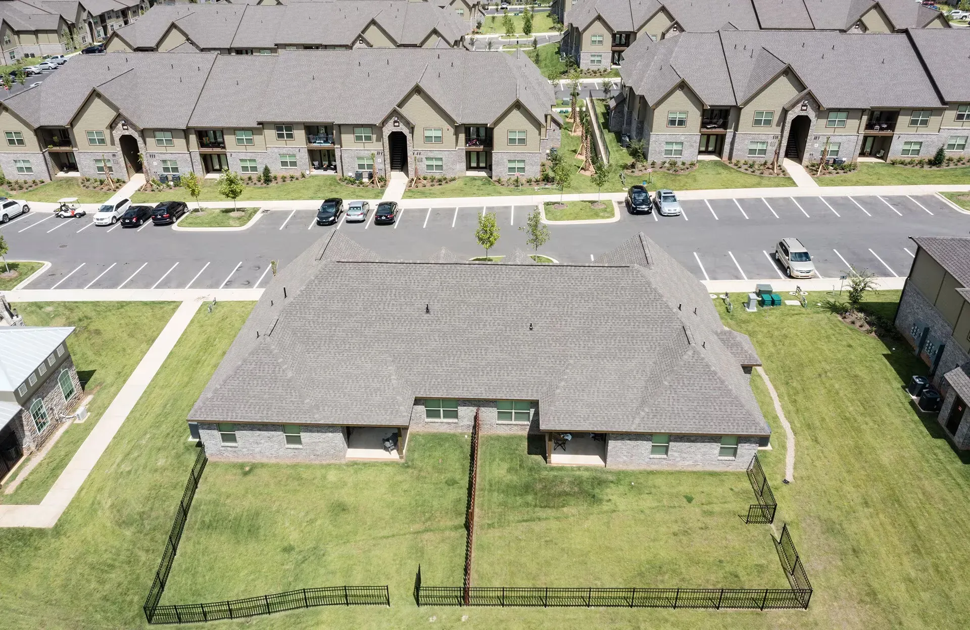 Aerial view of a multi-building apartment community with parking lots and green lawns.