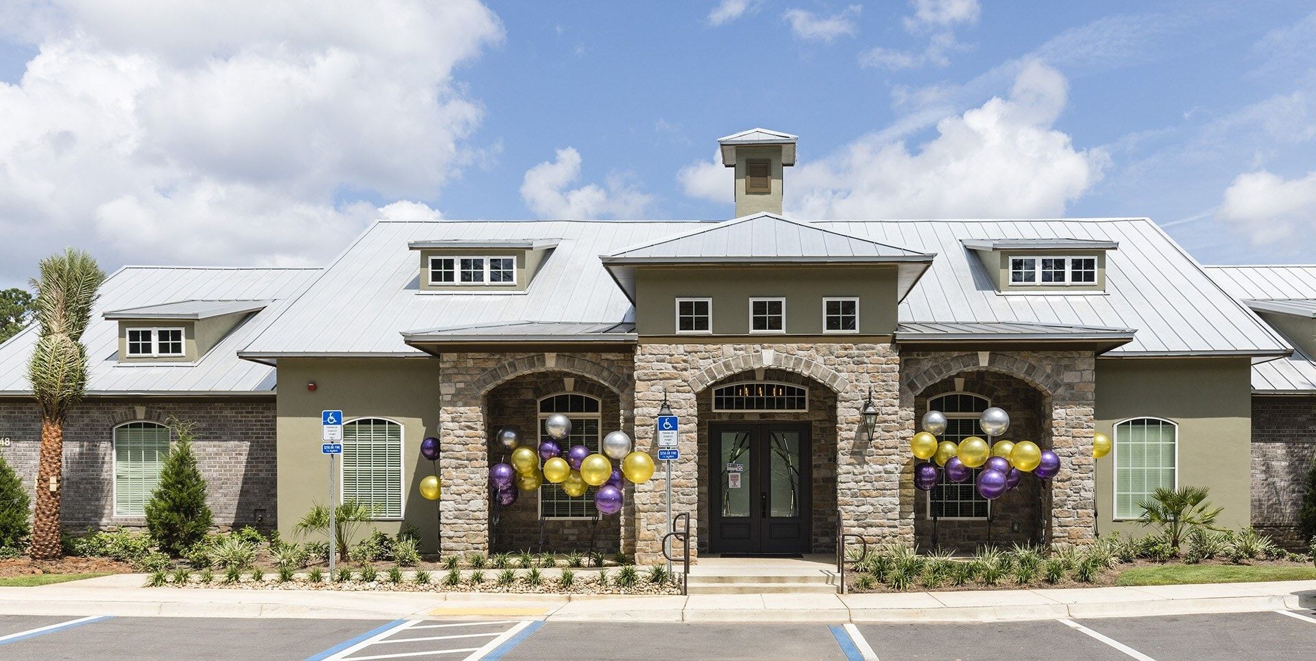 Exterior view of a multifamily community entrance with a stone archway and balloons