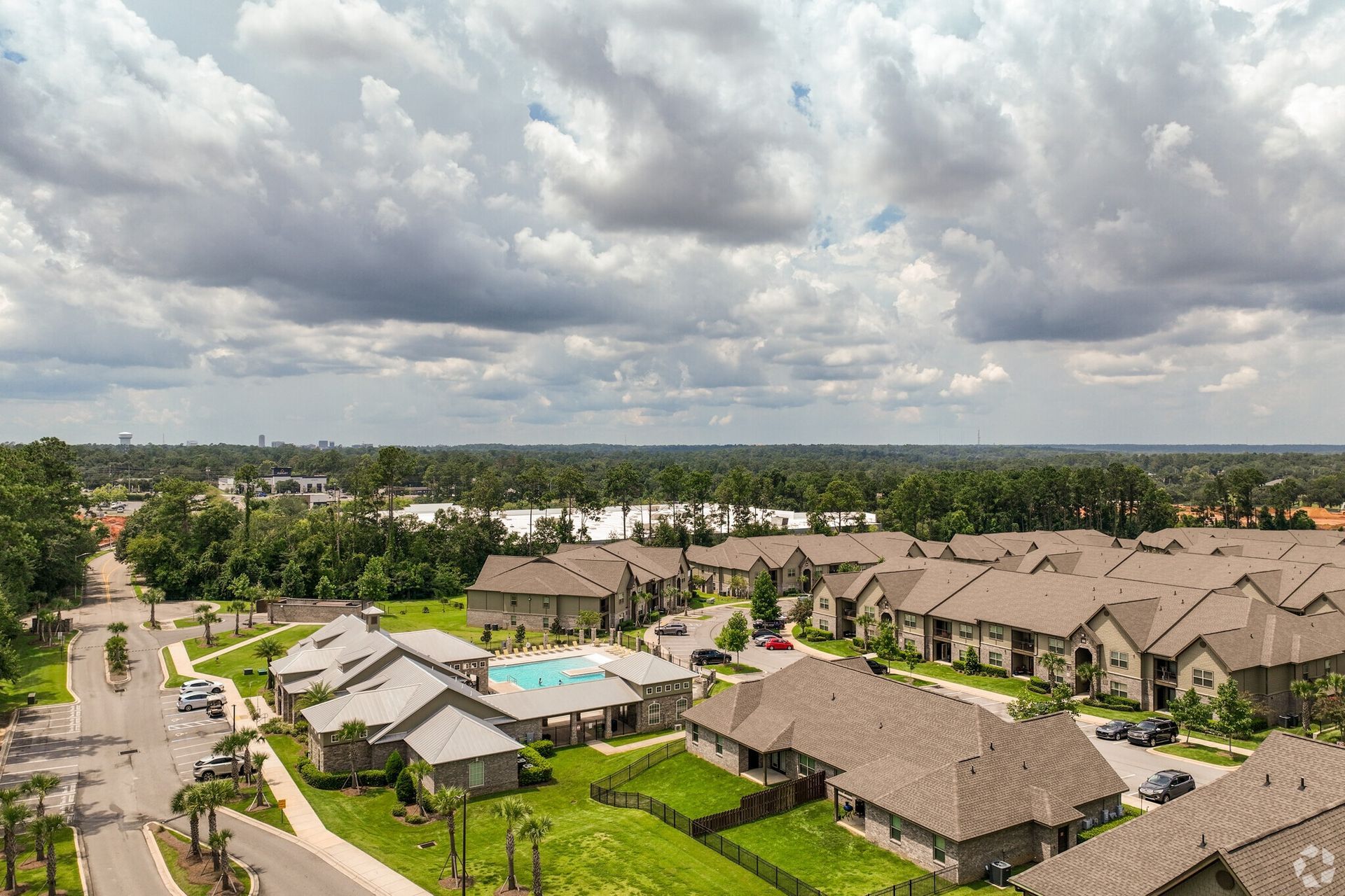 Aerial view of a suburban apartment community with a central pool and green courtyards.
