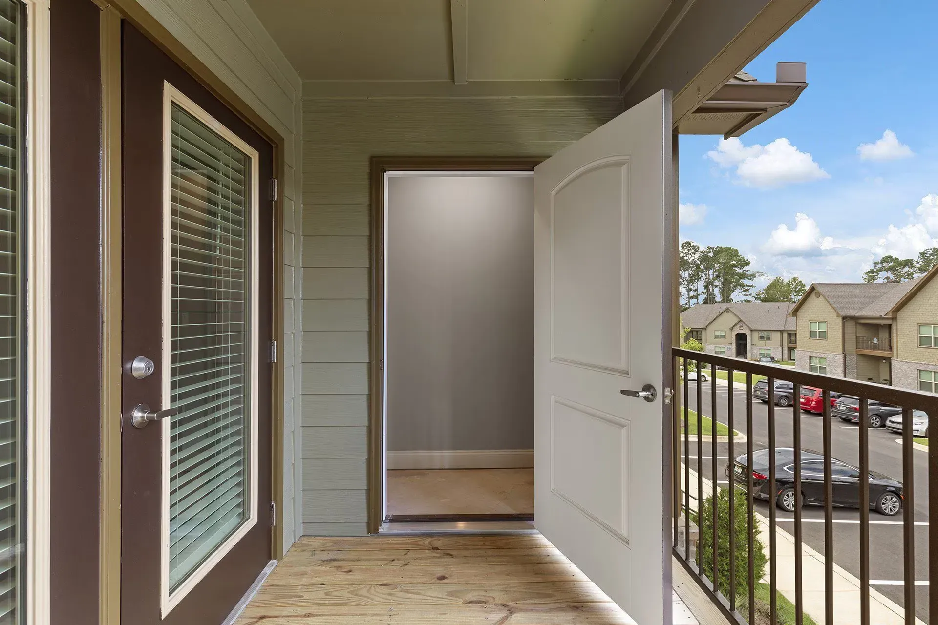Balcony doorway opening to view of parking lot and neighboring buildings