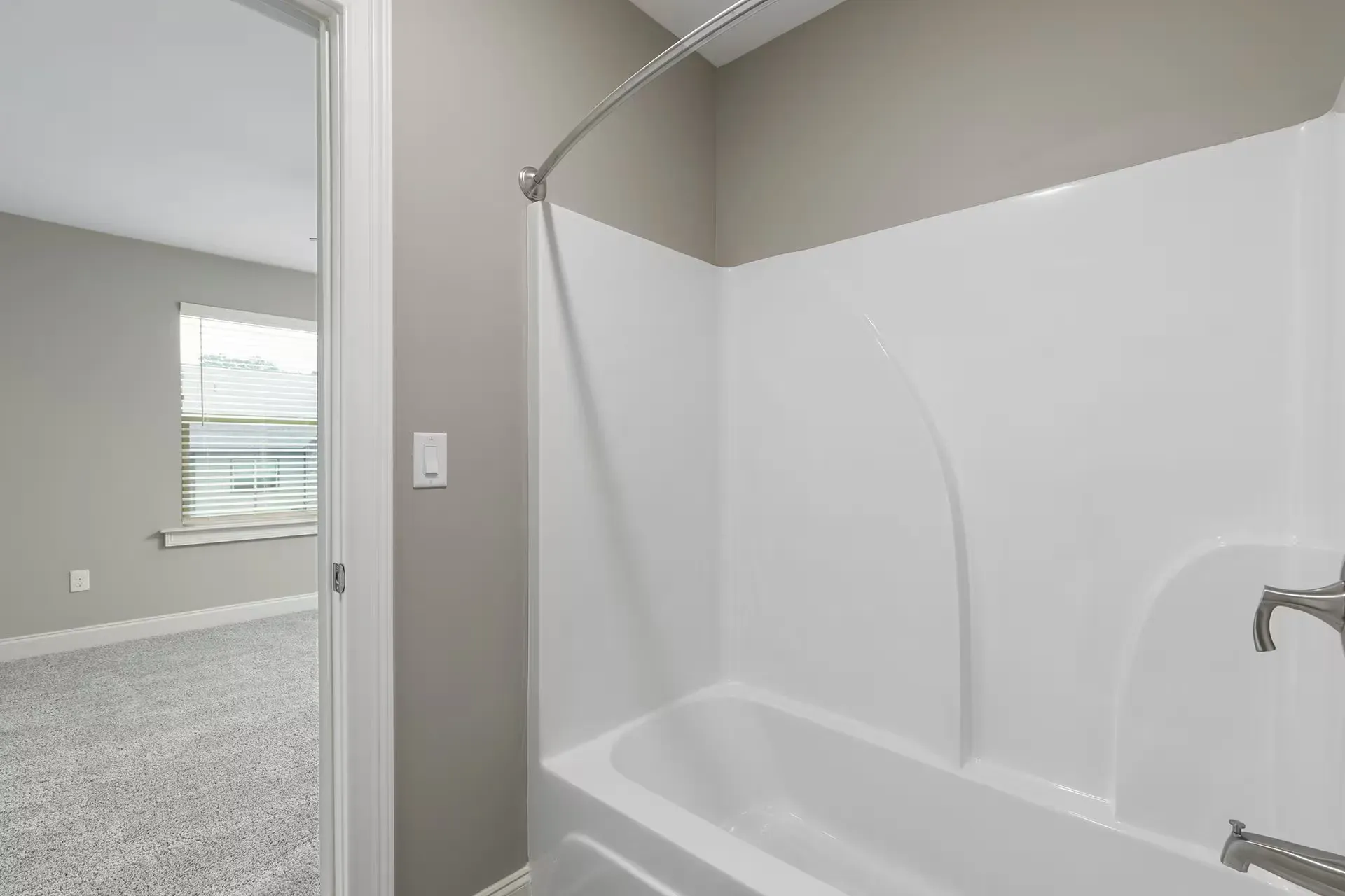 Bathroom in apartment with white tub/shower surround and curved shower rod.