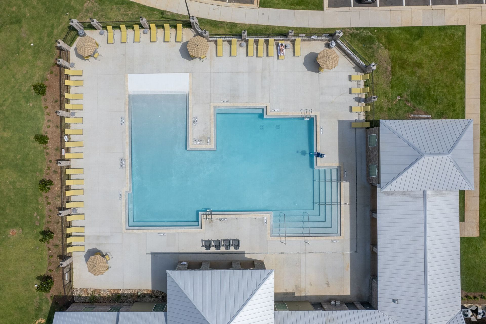 Aerial view of a rectangular pool surrounded by yellow lounge chairs and umbrellas in a courtyard.