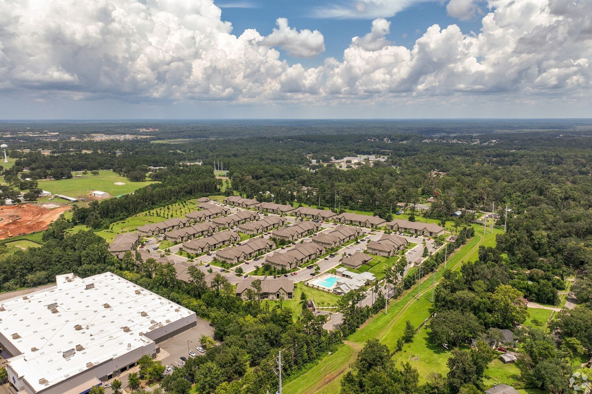 Aerial view of a large apartment community with multiple buildings, parking, and a central pool.