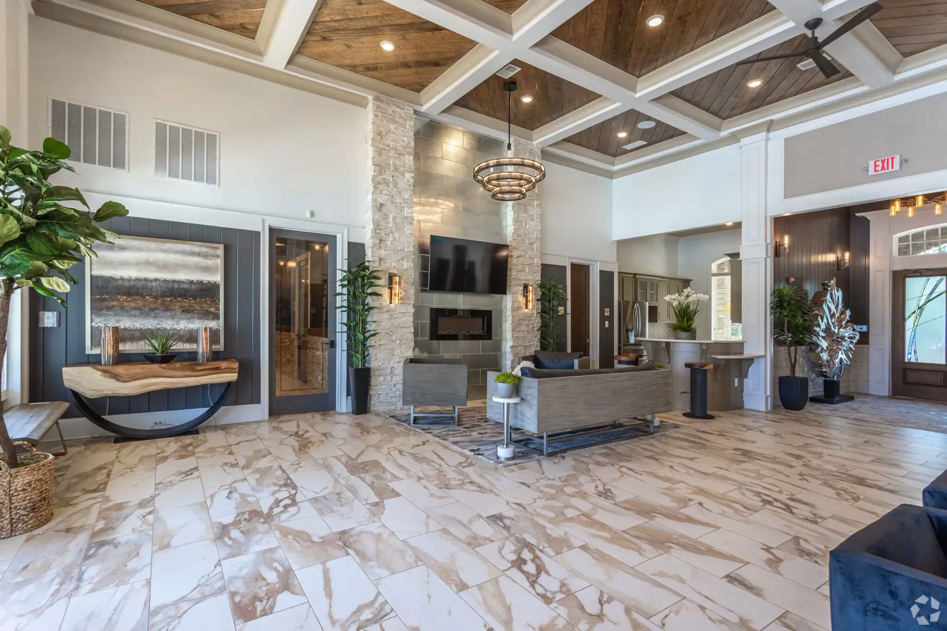 Spacious apartment lobby with marble tile flooring, a stone fireplace, and modern seating under a coffered ceiling.