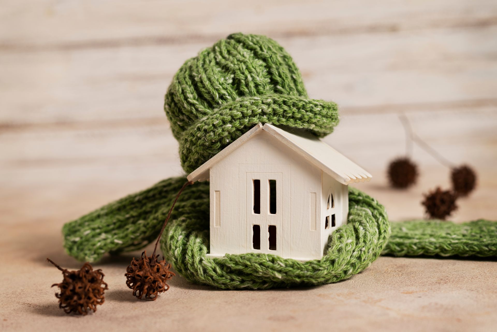 A small white house is wrapped in a green scarf and hat.