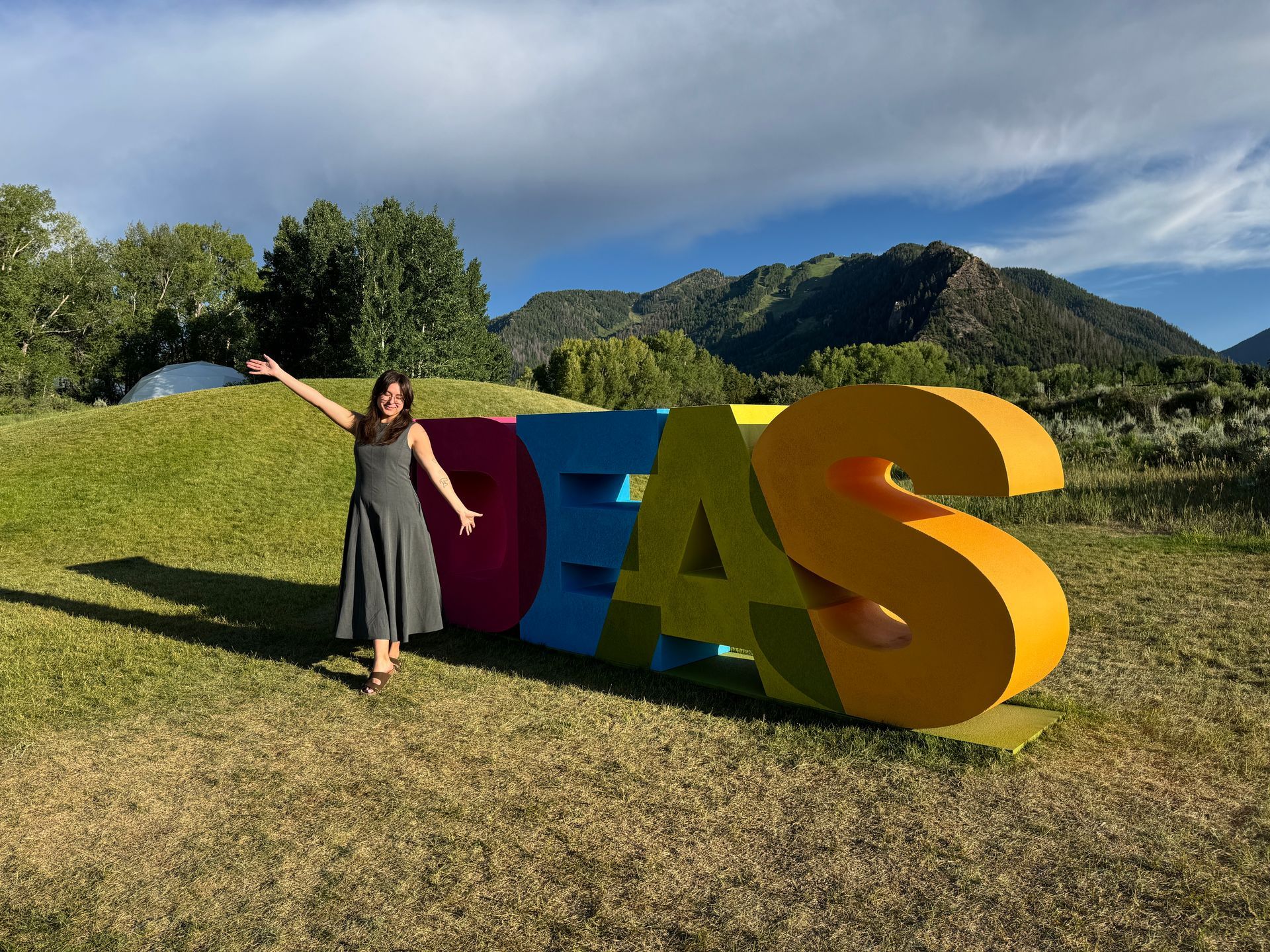 A person posing happily next to large, colorful 3D letters spelling 