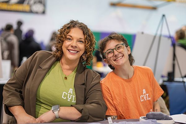 Two people smiling at a table, both wearing 