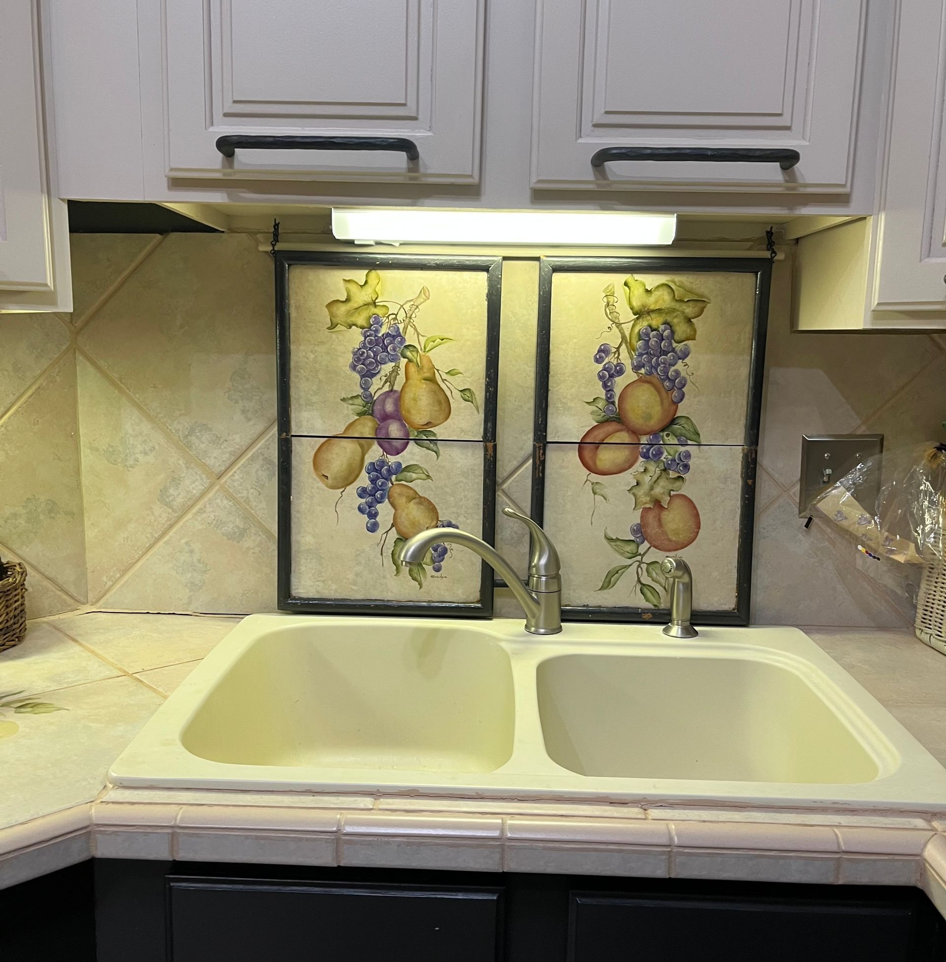 A man wearing orange gloves is fixing a gas stove in a kitchen.