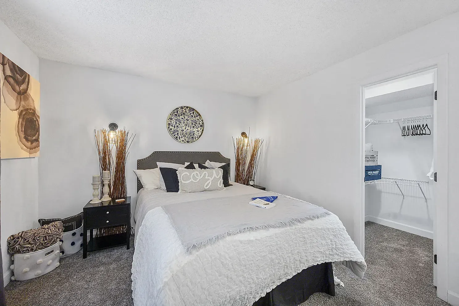 Tall Timber Apartments Furnished bedroom in an apartment with a bed, two nightstands, decorative lamps, and an open closet.