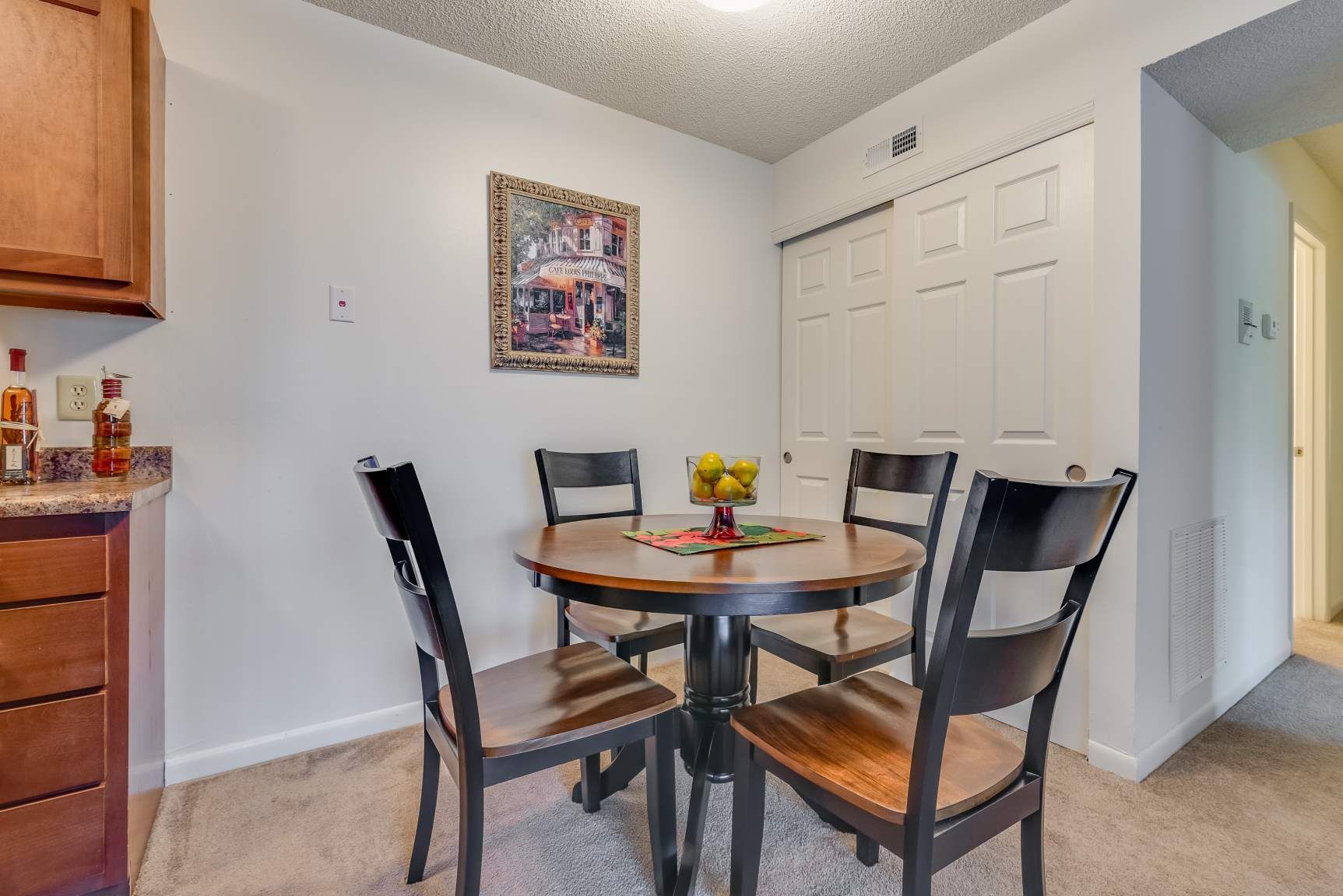 Tall Timber Apartments Dining area inside apartment with round wooden table and four dark chairs.