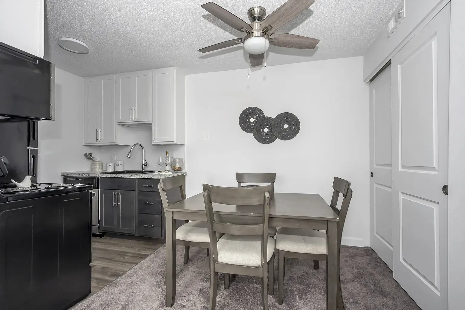 Tall Timber Apartments kitchen and dining area with white cabinets, black appliances, and a dining table.
