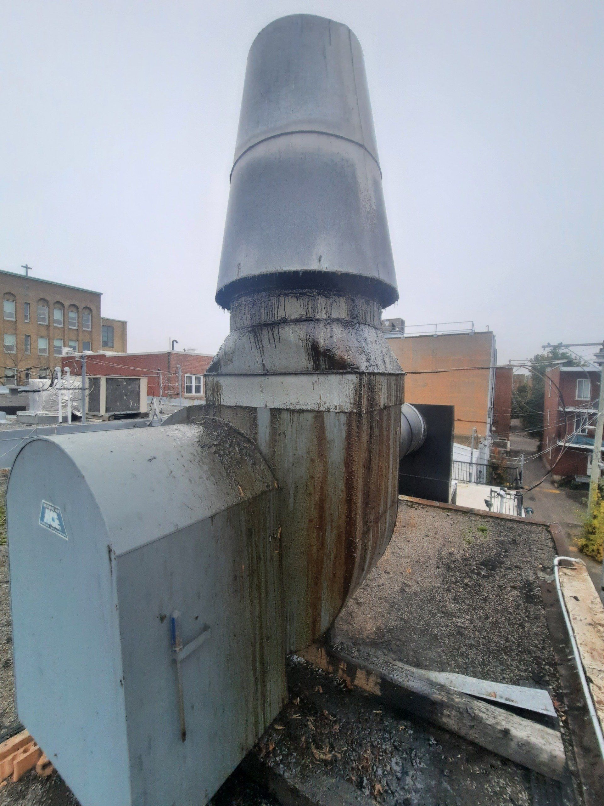 Un ventilateur d’extraction rouillé se trouve au sommet d’un toit.