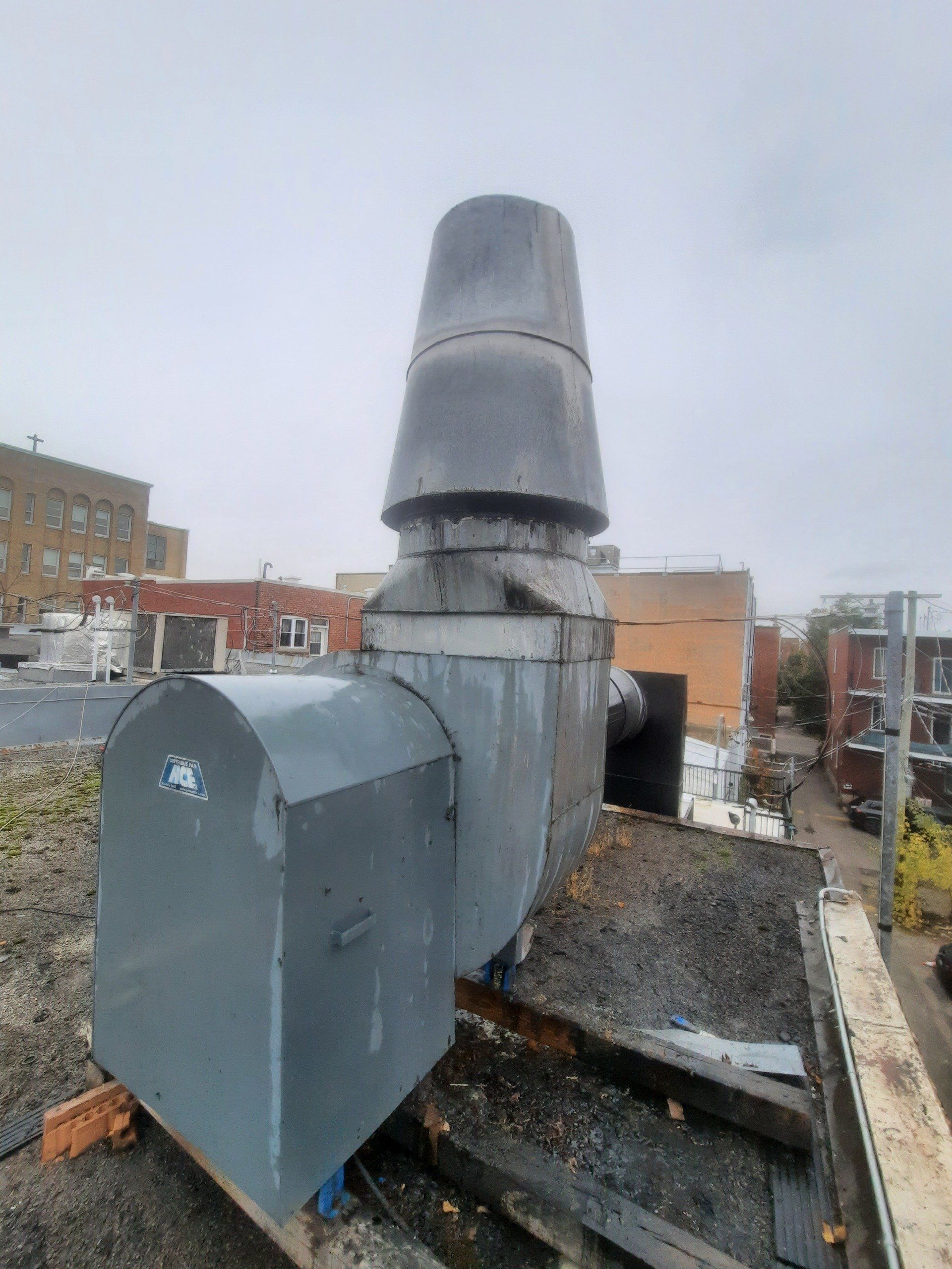 Un grand ventilateur d’extraction se trouve sur le toit d’un immeuble.