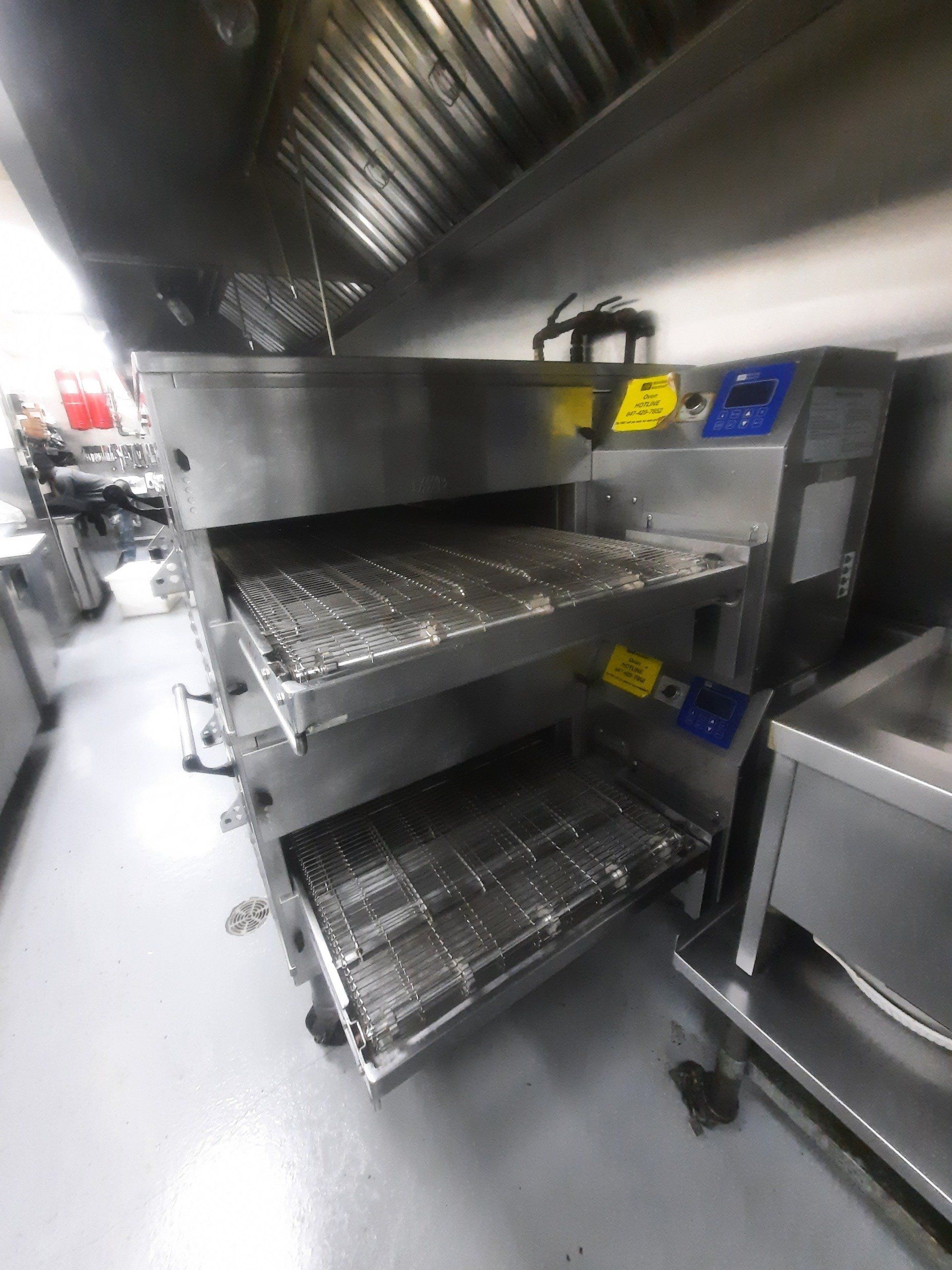 Un four à pizza en acier inoxydable se trouve dans une cuisine.