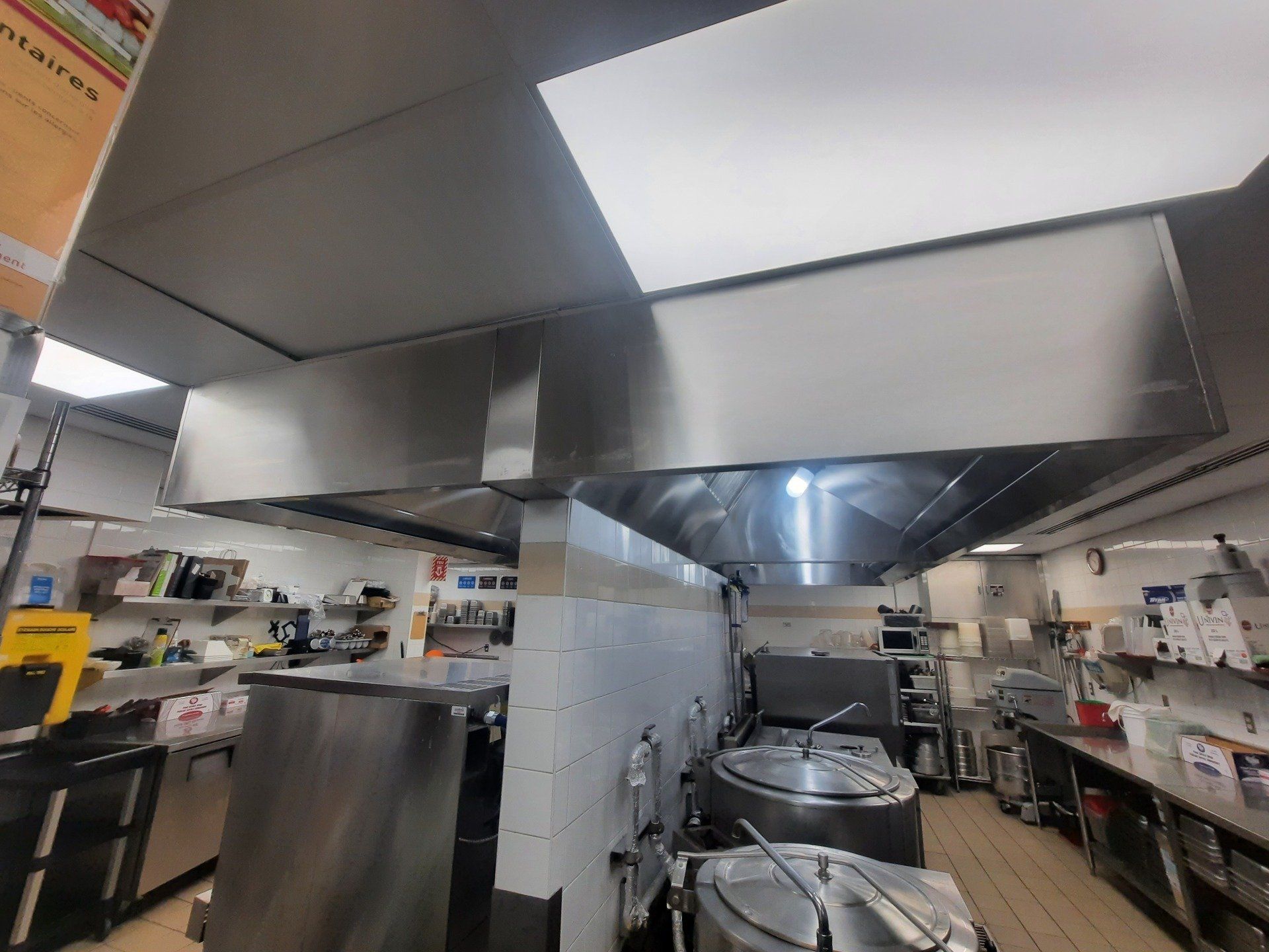 Une cuisine avec appareils électroménagers et casseroles et poêles en acier inoxydable