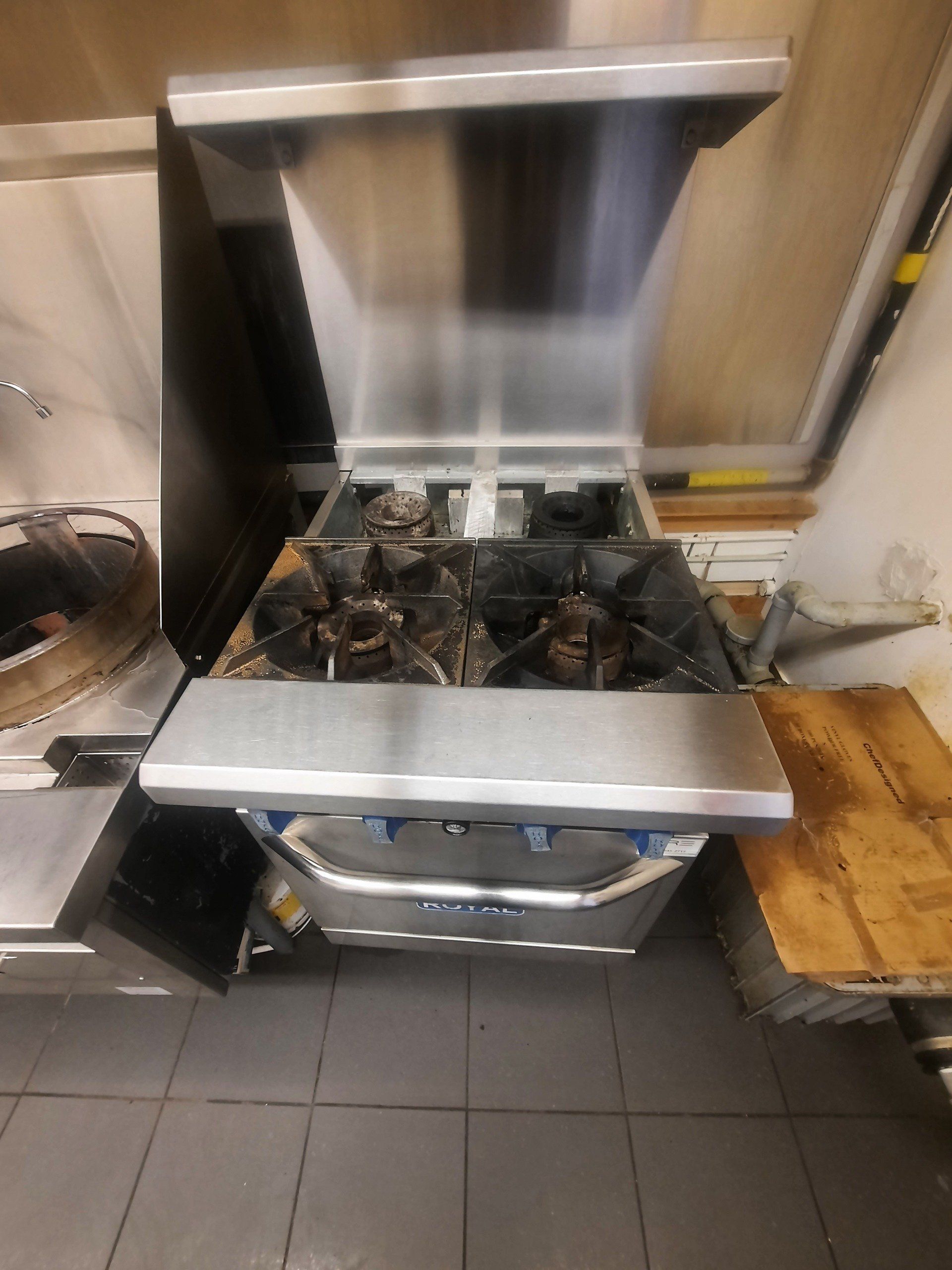 Une cuisinière en acier inoxydable est posée sur un sol carrelé dans une cuisine.