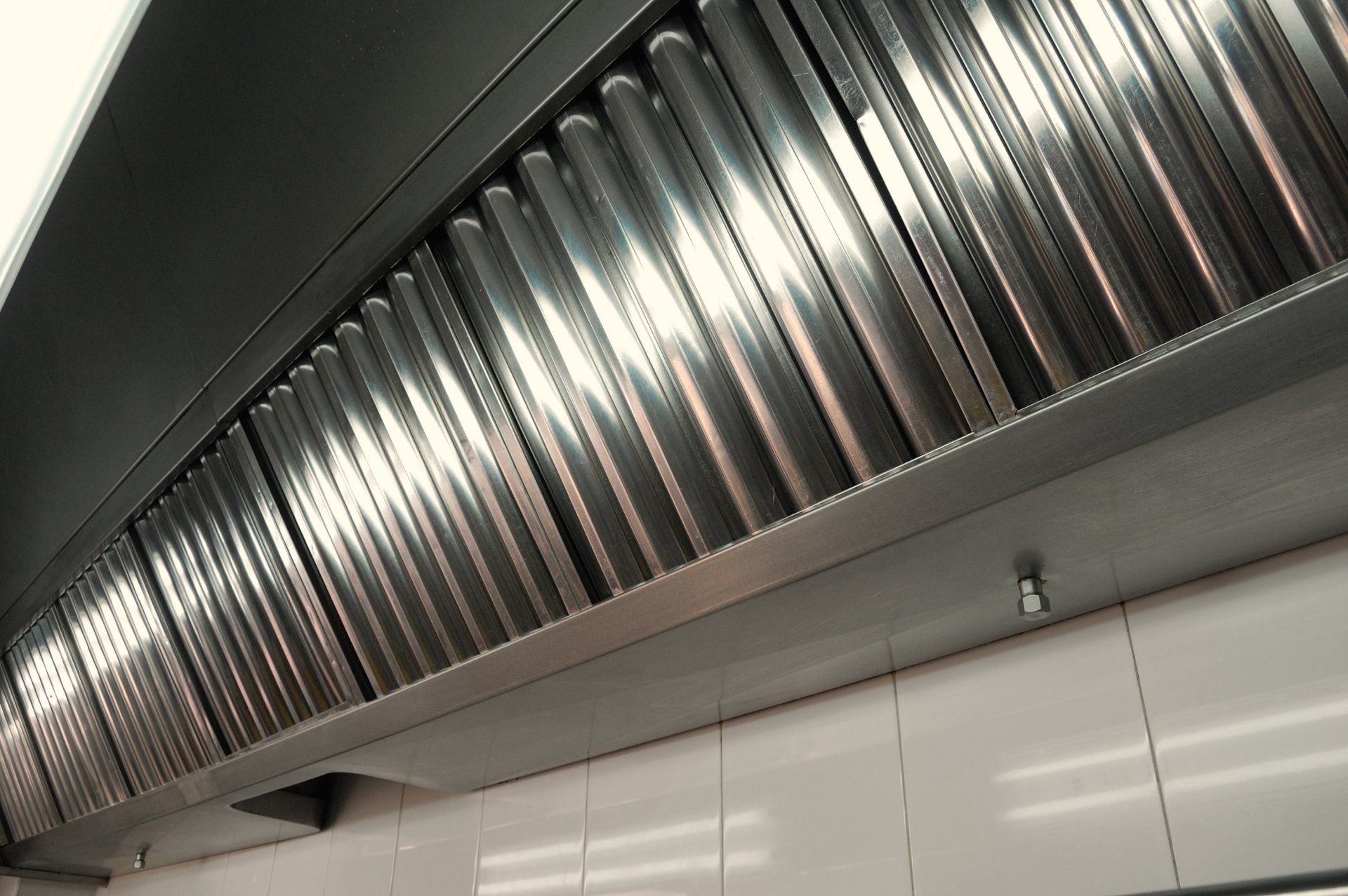 Une hotte aspirante en acier inoxydable est suspendue au plafond d une cuisine.