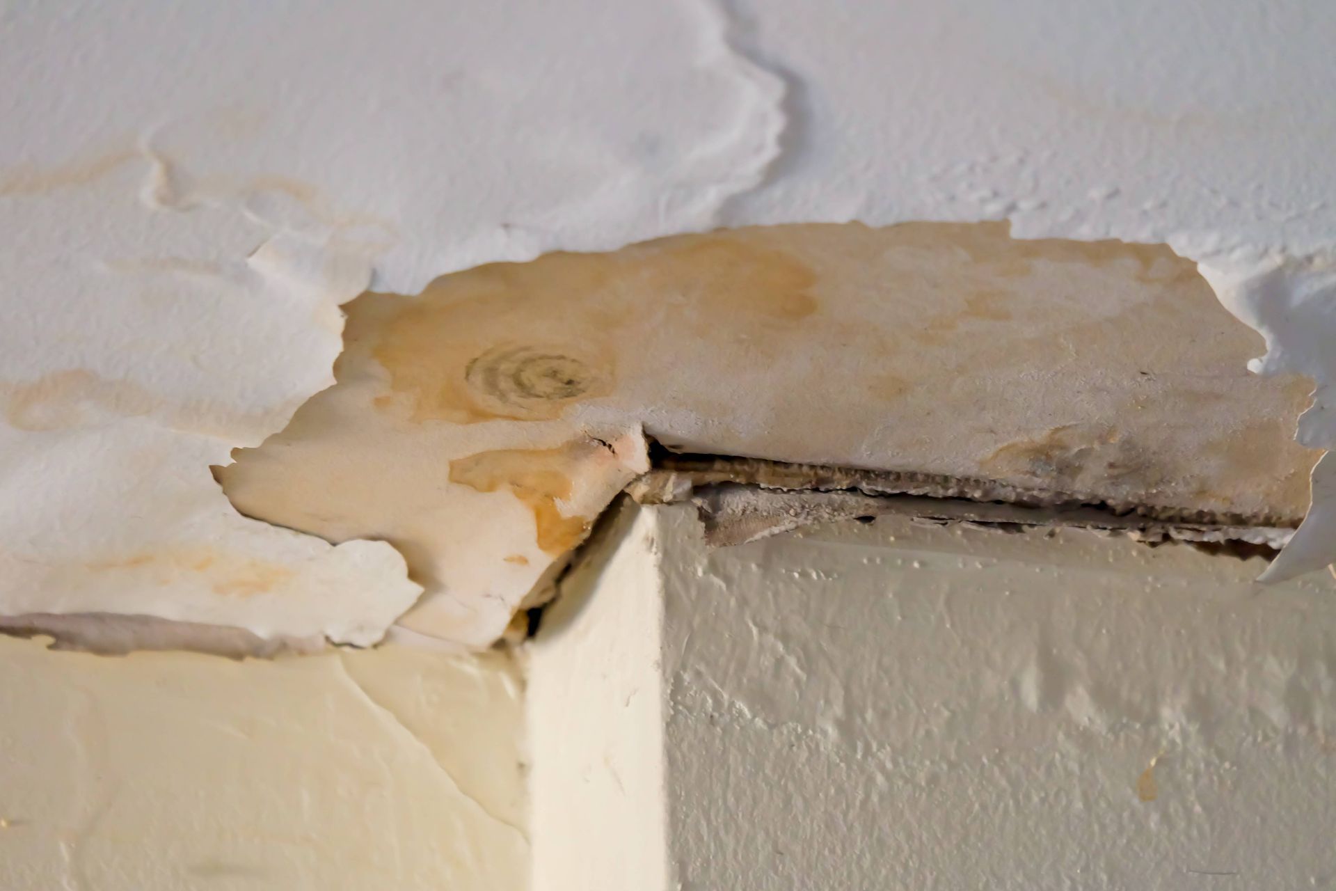 a corner of a wall with peeling paint and a hole in it