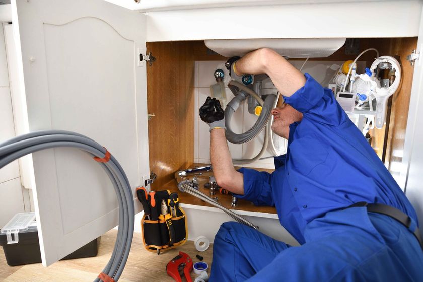 a plumber works under a sink in a bathroom