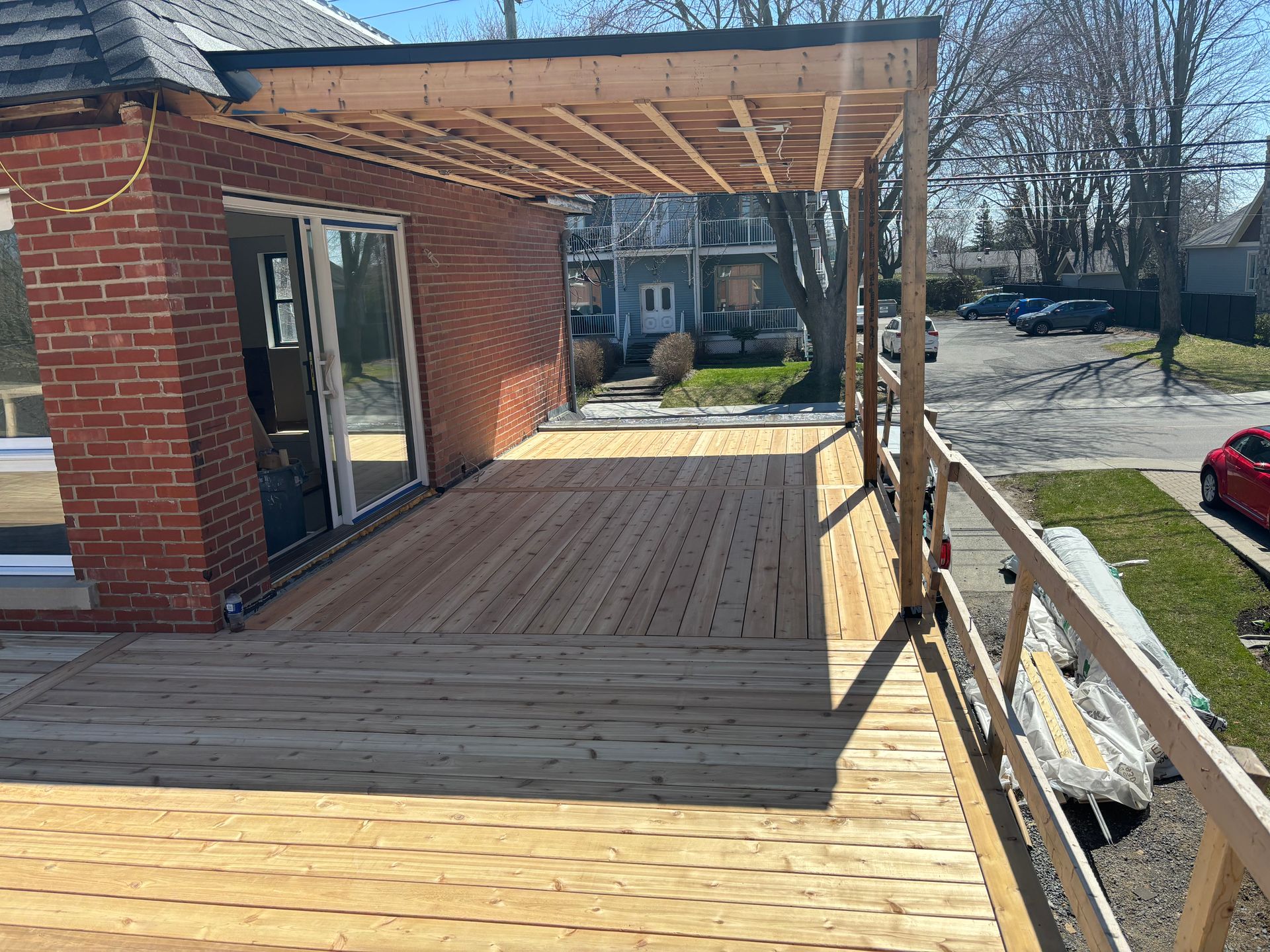 Une terrasse en bois est en cours de construction sur le côté d'une maison en briques.