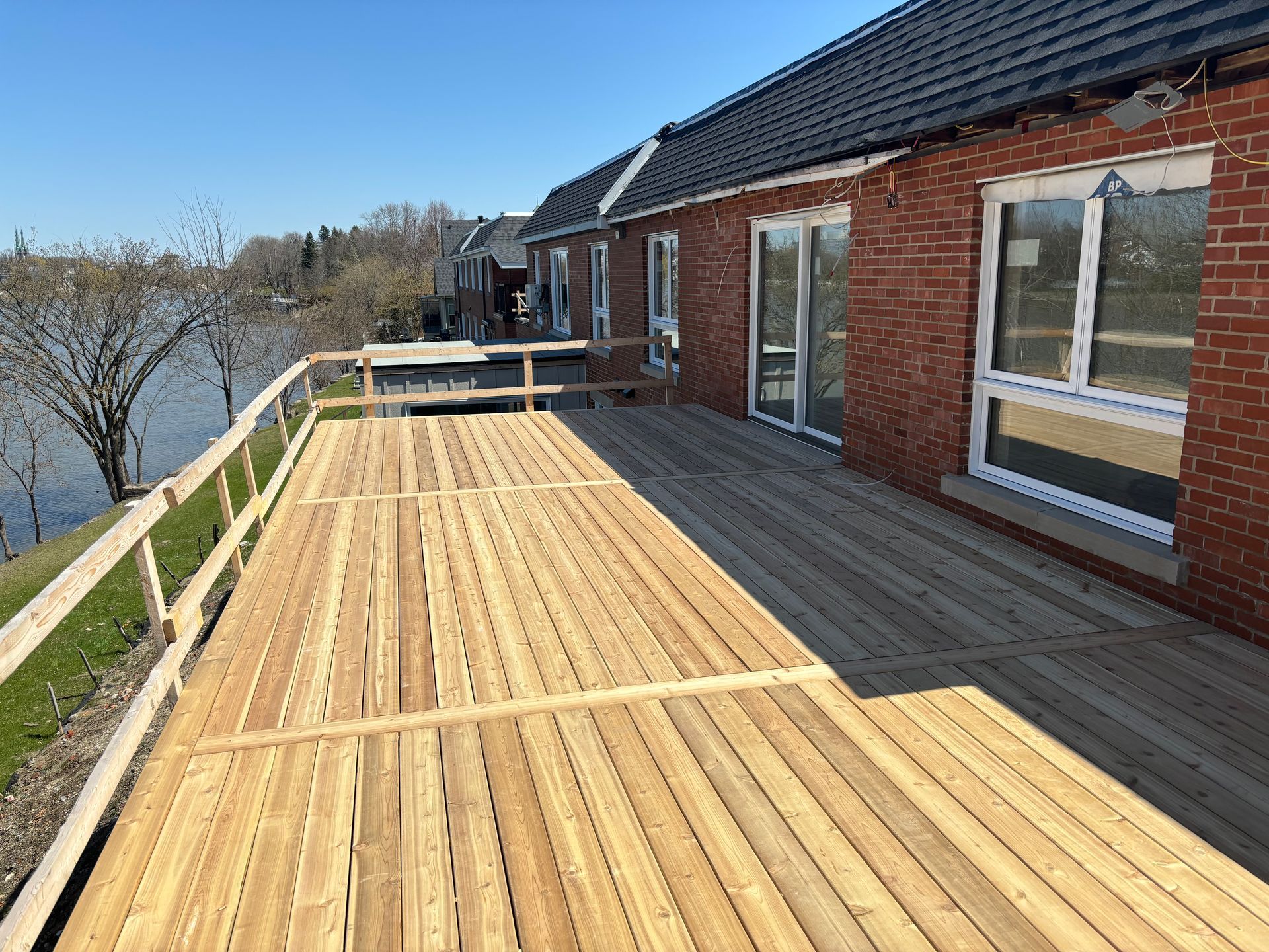 Il y a une grande terrasse en bois devant un bâtiment en briques.