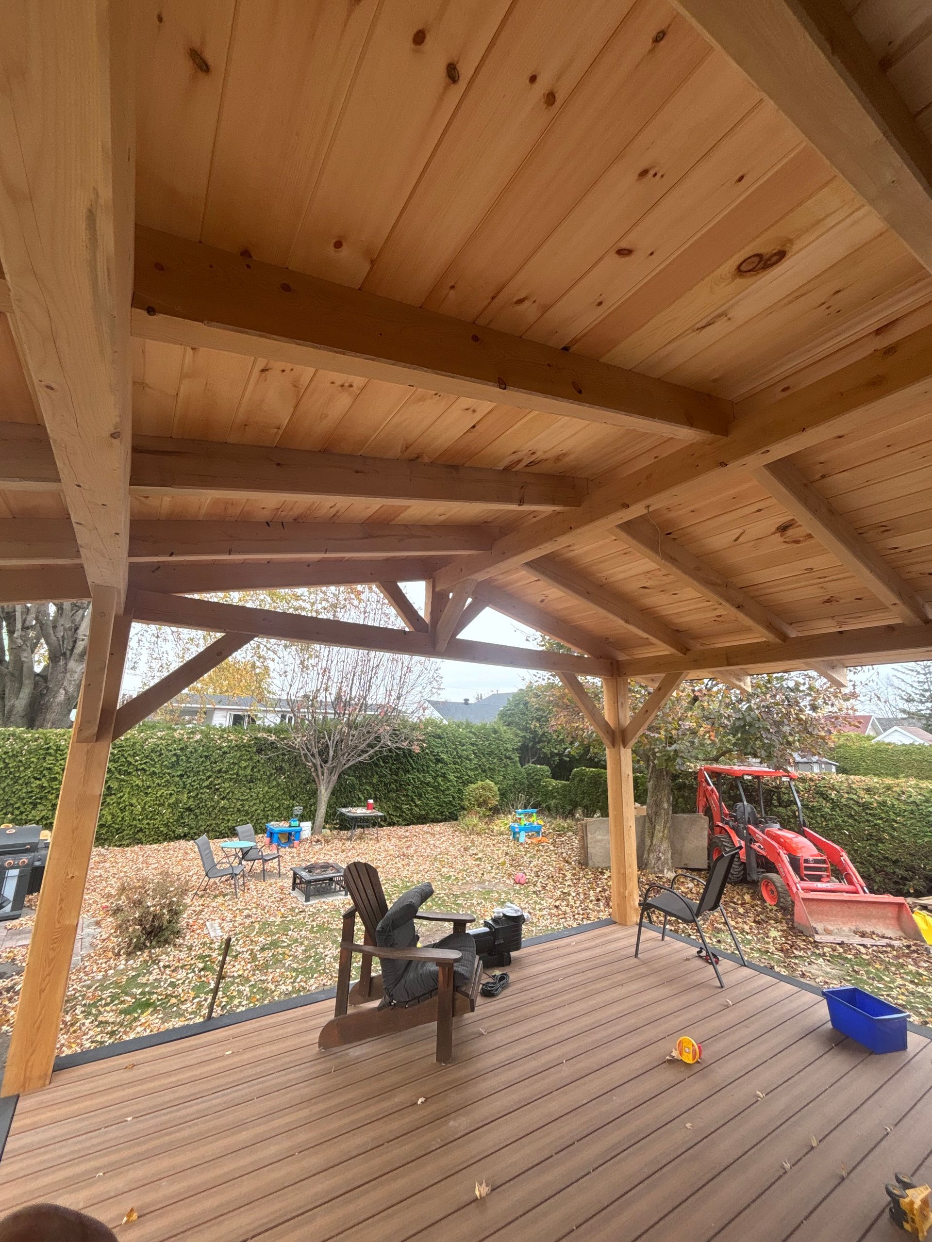 Une personne est assise sur une chaise sur une terrasse en bois sous un toit en bois.