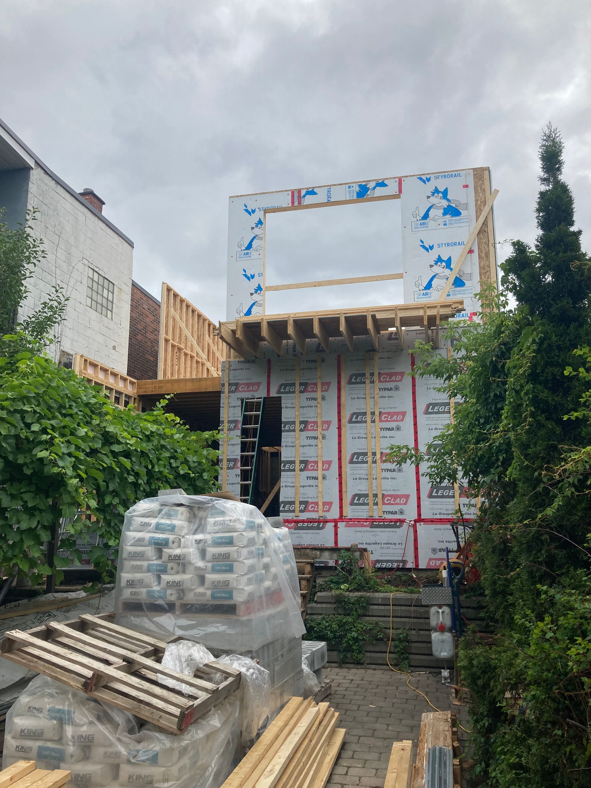 Une maison est en construction avec beaucoup de fournitures devant elle.