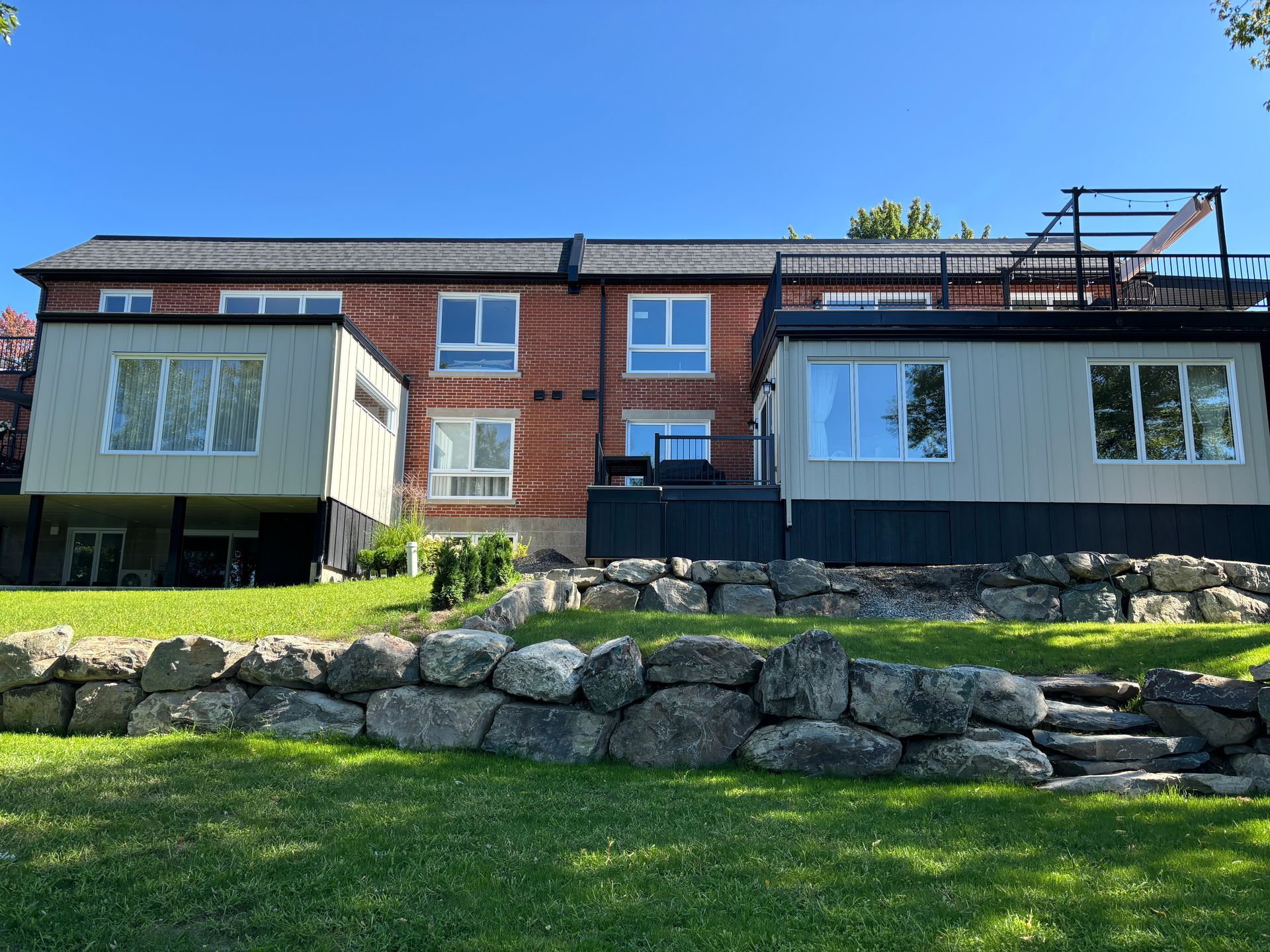 L'arrière d'une grande maison en briques avec un mur de pierre devant.