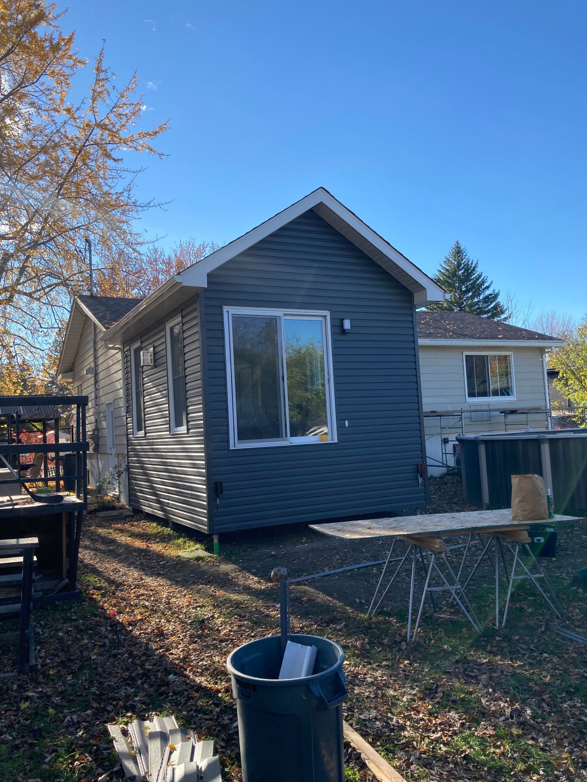 Une petite maison avec une poubelle devant.