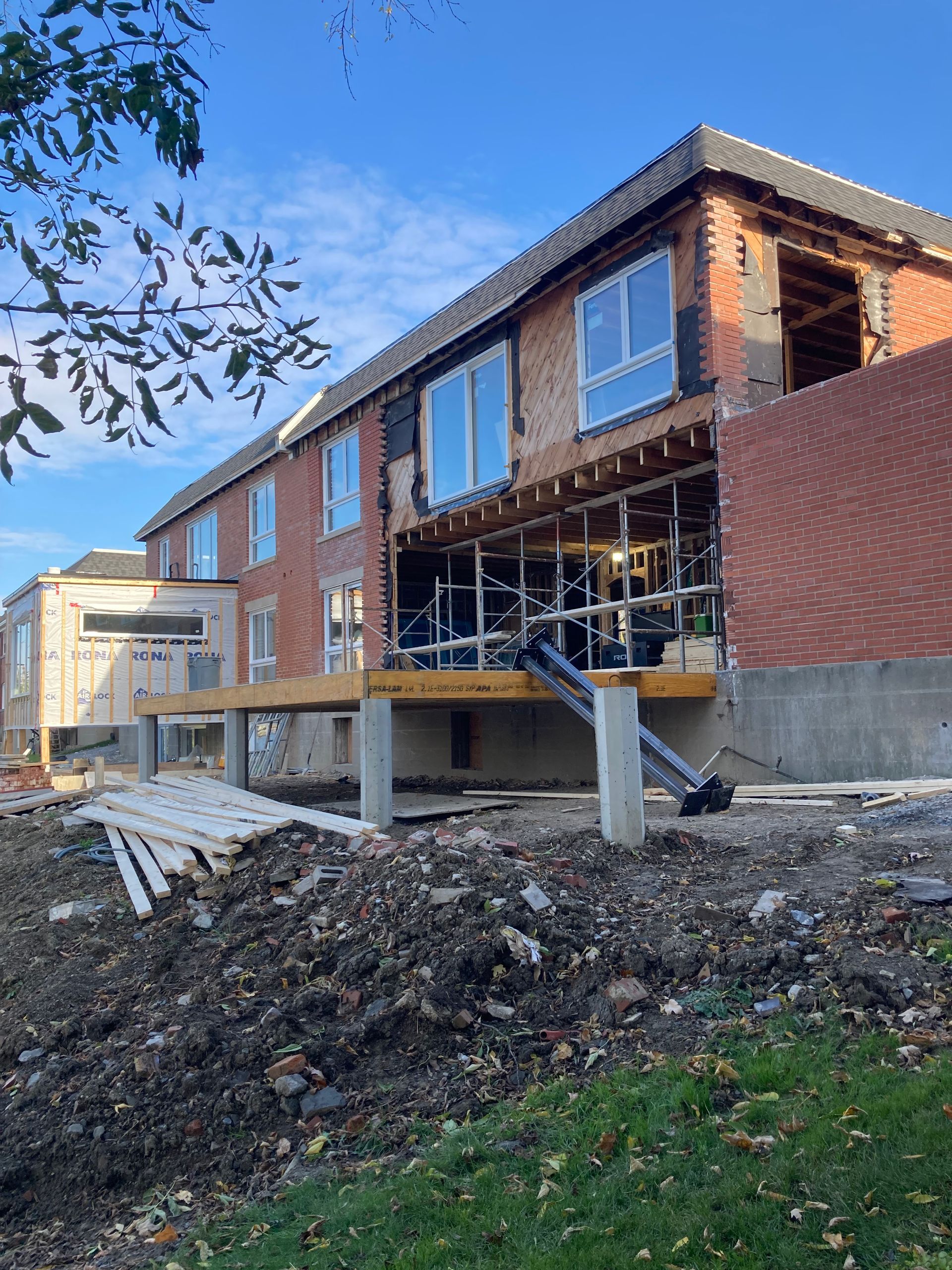 Un grand bâtiment en briques est en cours de construction au sommet d'une colline de terre.