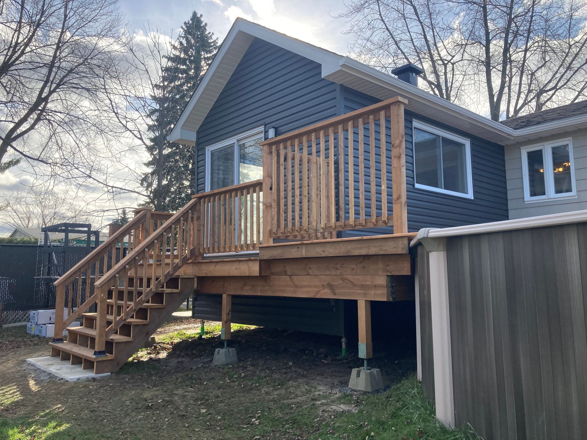Une petite maison avec une terrasse en bois et des escaliers.