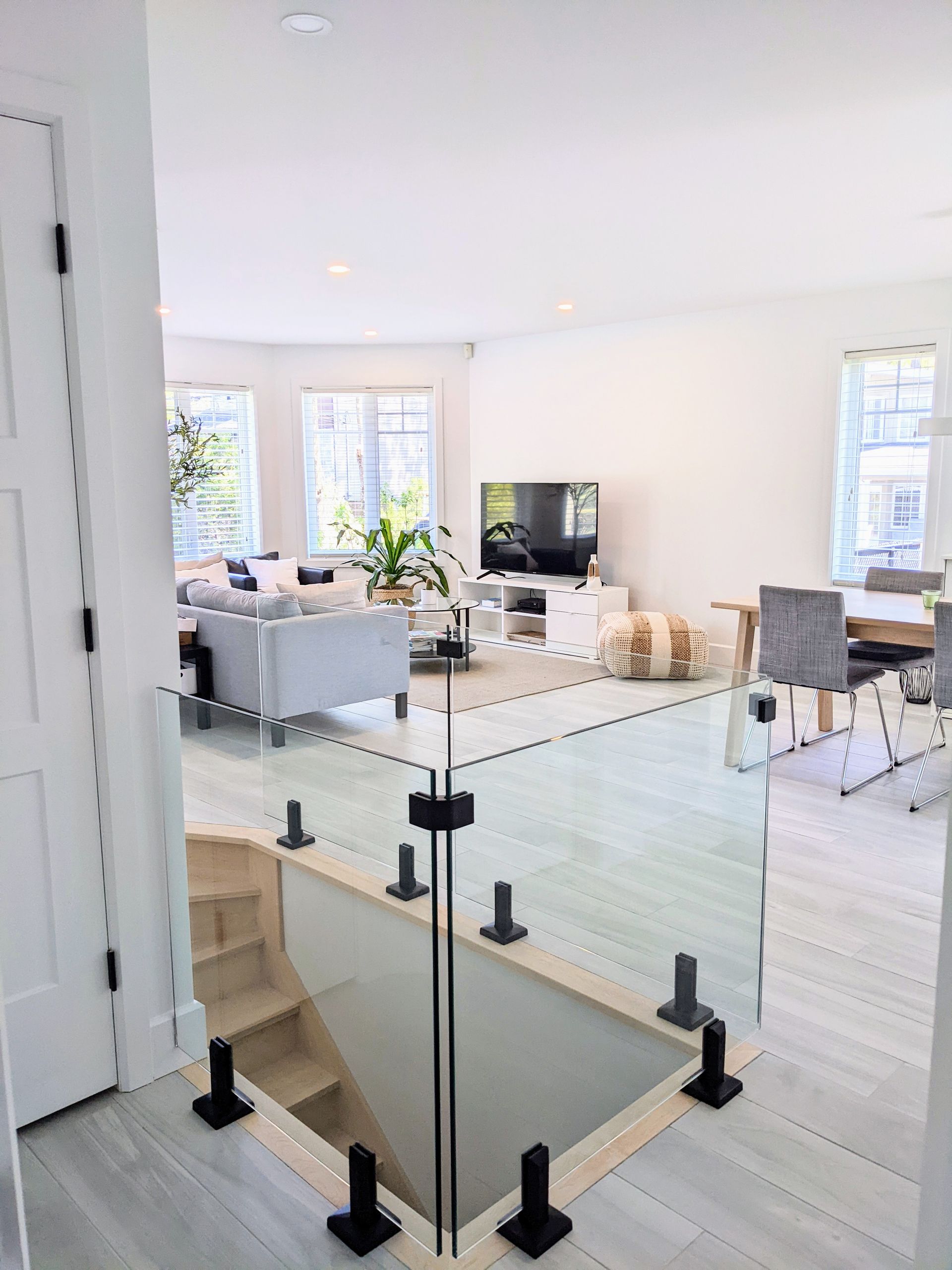 Un salon avec une balustrade en verre et des escaliers