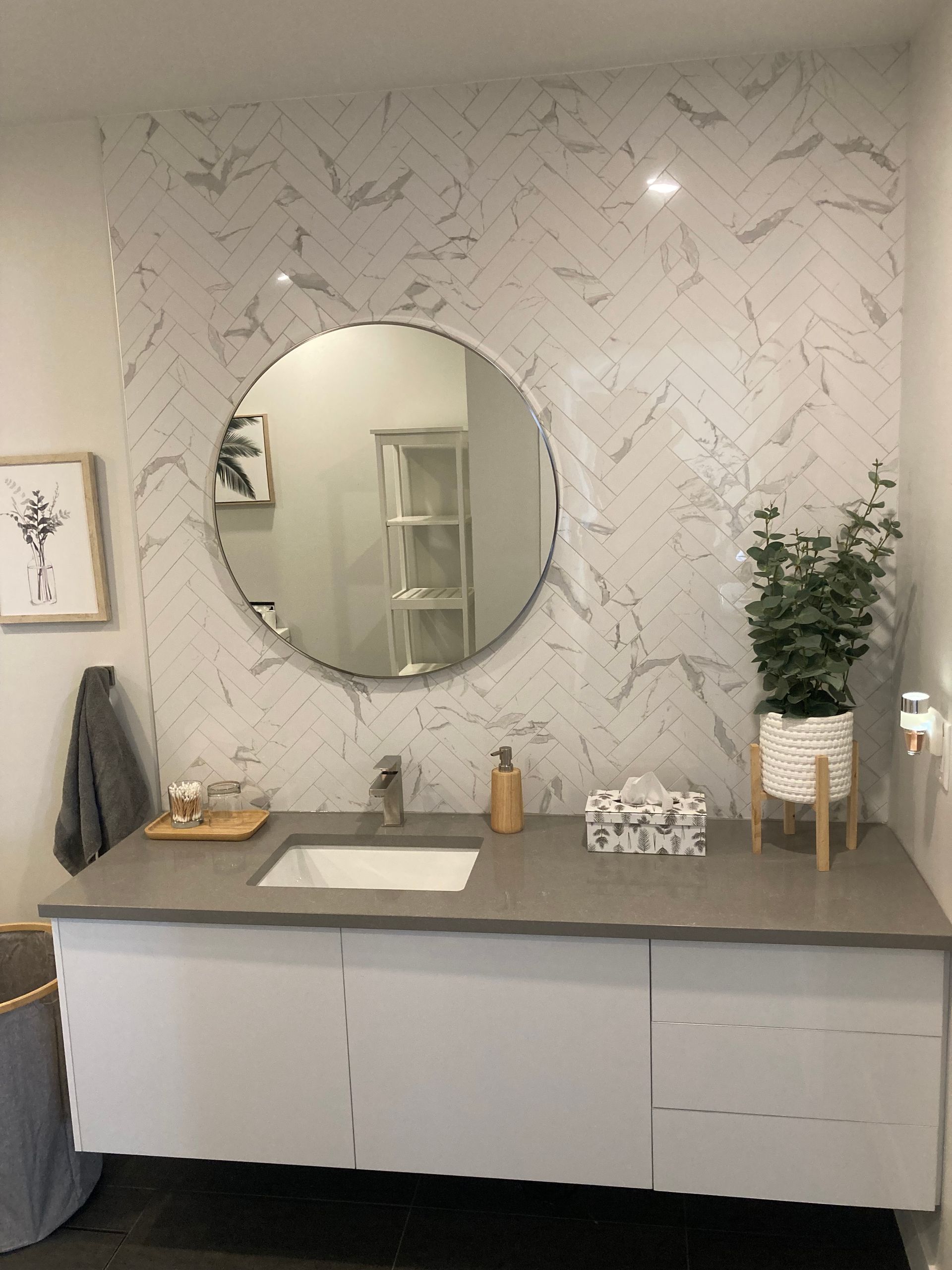 Une salle de bain avec un lavabo et un miroir rond.