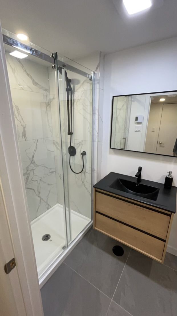 Une salle de bain avec douche, lavabo et miroir.