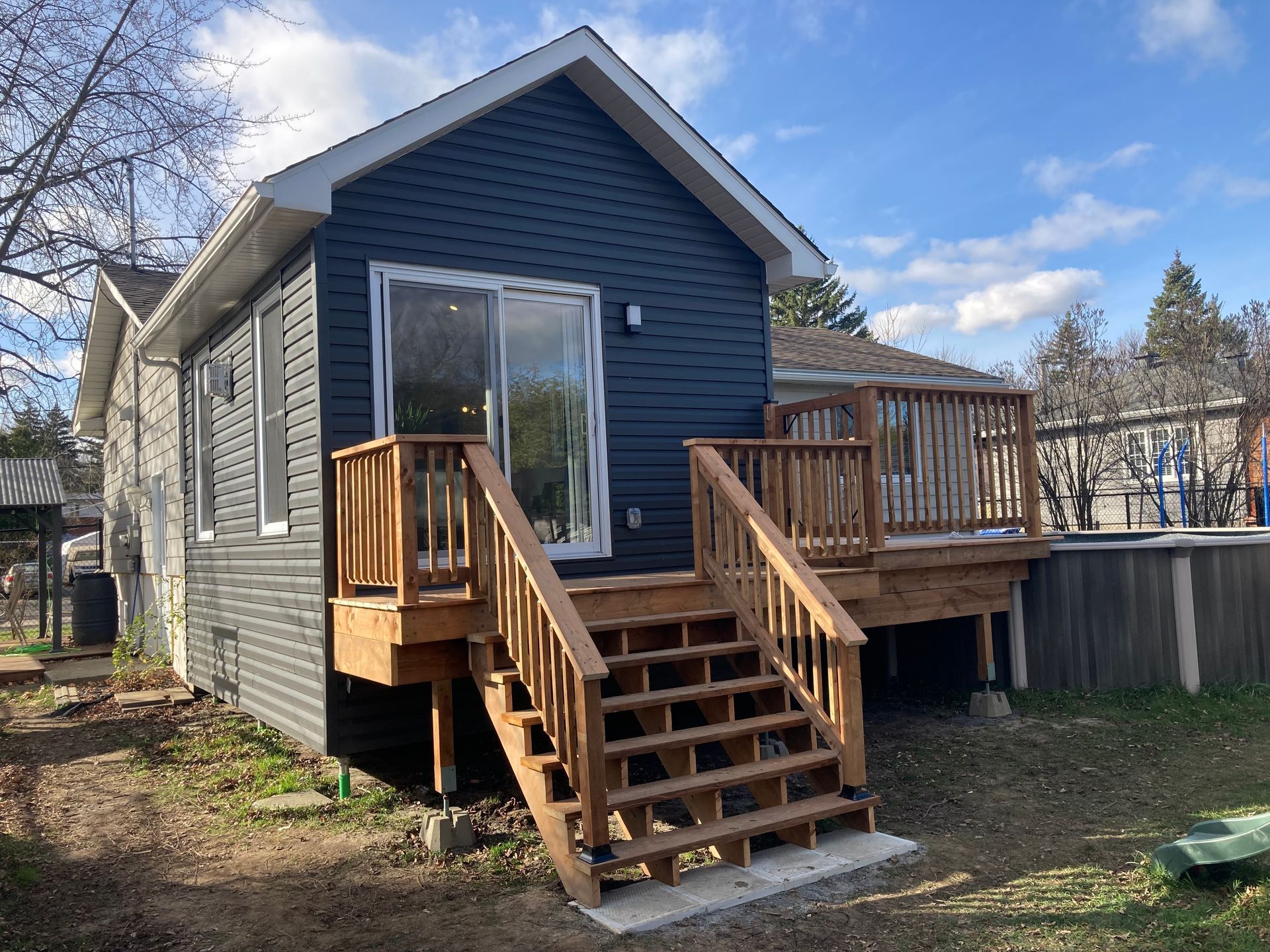 Une petite maison avec une terrasse et des escaliers devant.