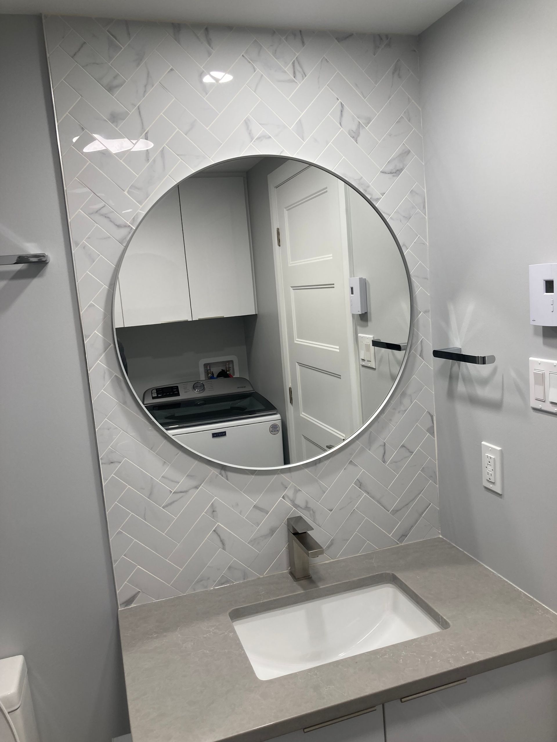 Une salle de bain avec un miroir rond et un lavabo.