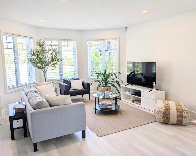 Un salon avec un canapé, des chaises, une table basse et une télévision.