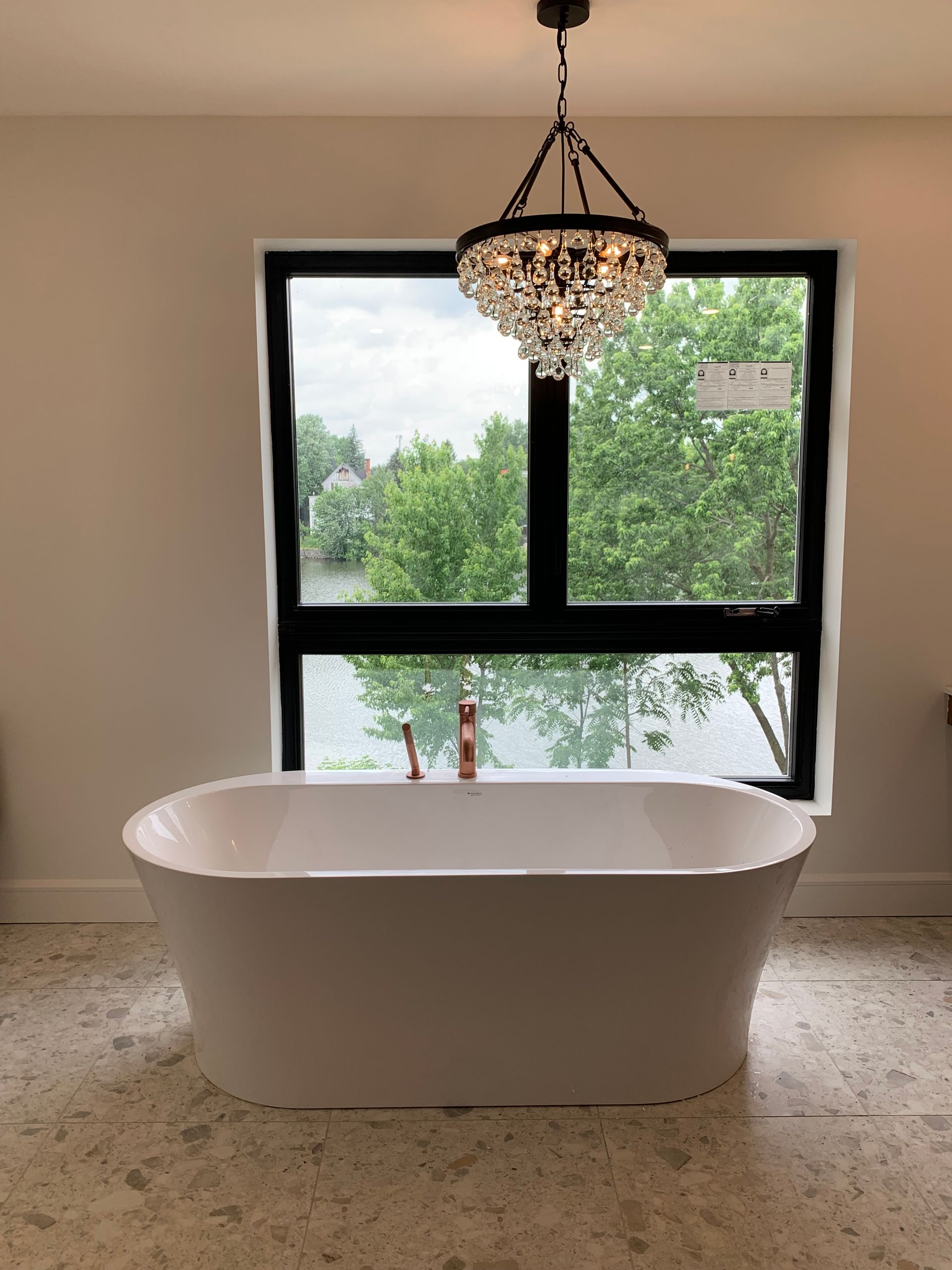 Une baignoire dans une salle de bain avec une fenêtre et un lustre