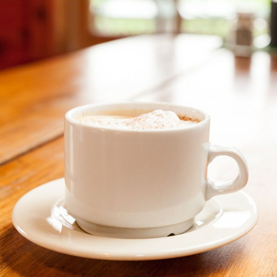 A cup of coffee on a saucer on a wooden table