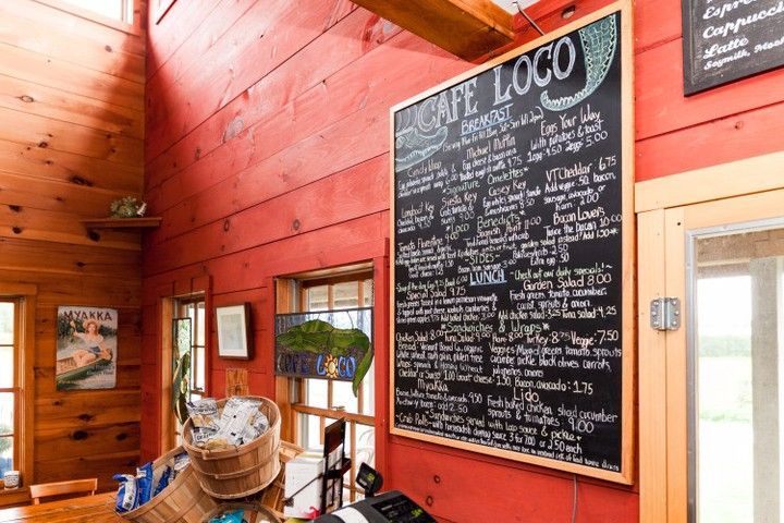 A large blackboard is hanging on a red wall in a restaurant.