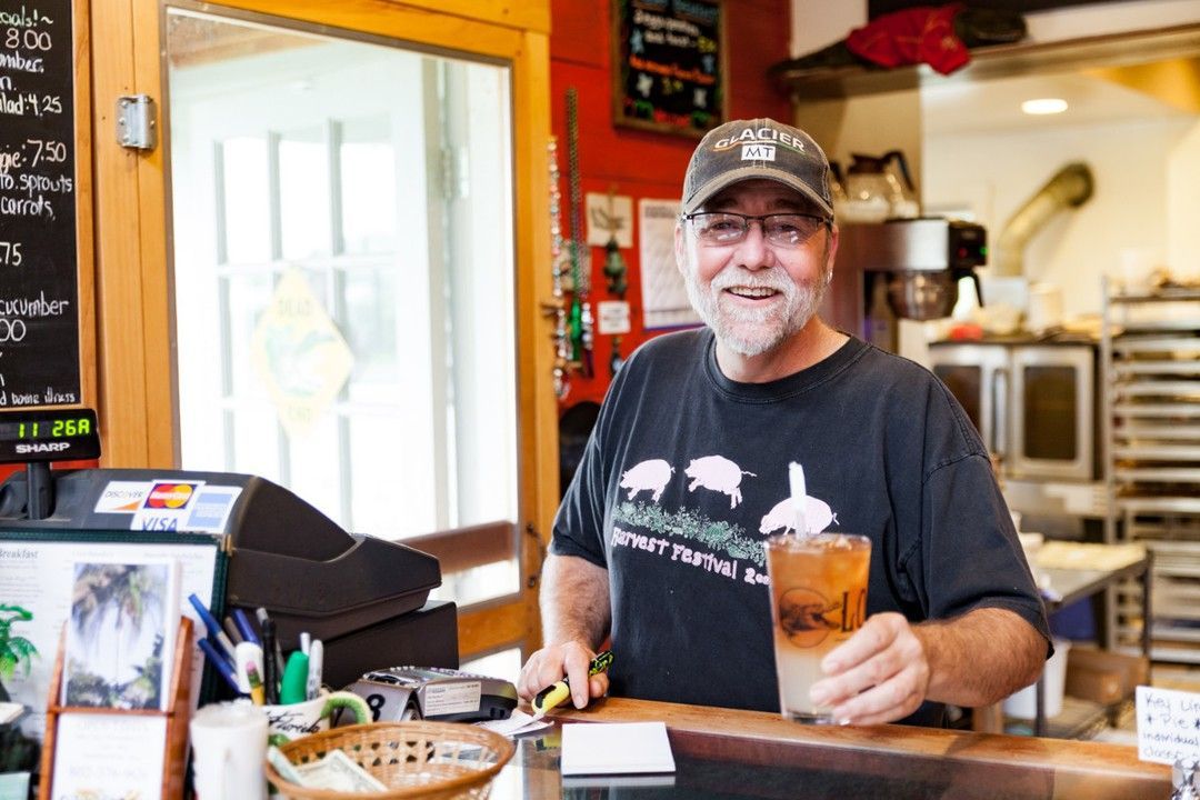 A man is standing behind a counter in a restaurant holding a drink.